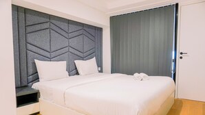 A modern bedroom with a geometric headboard, a neatly made bed with white linens, and a wooden floor.