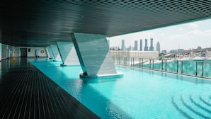 Ein modernes Hallenbad mit Blick auf eine Stadtlandschaft, das sich durch ein elegantes Architekturdesign, ein Holzboden und eine Metallgeländer auszeichnet.