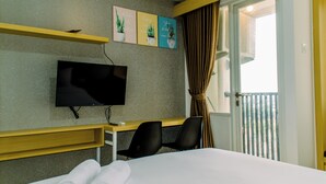 A hotel room with a bed, a desk with a chair, a flat-screen TV, and a balcony with curtains. - Nice Studio Apartment At Urban Height Residence (South Tangerang)