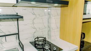 A kitchen with a Rinnai gas stove, a stainless steel sink, and a marble backsplash. - Nice Studio Apartment At Urban Height Residence (South Tangerang)