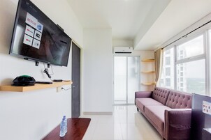 Una sala de estar moderna con televisor de pantalla plana, sofá, mesa de centro y una botella de agua.