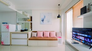 A modern living room with a sofa, TV, and a kitchen area with a refrigerator and microwave. - Best Choice And Restful Studio Signature Park Grande Apartment (Jakarta)