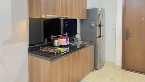Een kleine keuken met houten kastjes, een zwart aanrecht, een roestvrijstalen koelkast en een inbouwoven.