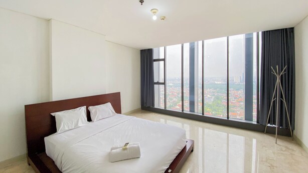 Een hotelkamer met een groot bed, uitzicht op de stad door middel van kamerhoge ramen, en een modern design.