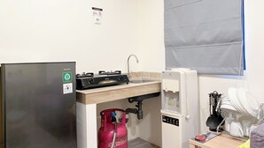 A compact kitchen with a refrigerator, a gas stove, a sink, and a water dispenser. - Good Deal And Comfortable 2Br Meikarta Apartment (Cikarang)
