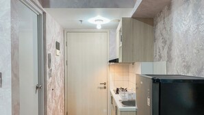 Una cocina estrecha con encimera de madera, un refrigerador negro y una puerta blanca.