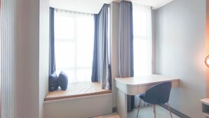 A hotel room with a window seat, a desk, and a chair. - Beautiful And Modern Studio At Benson Supermall Mansion Apartment (Surabaya)