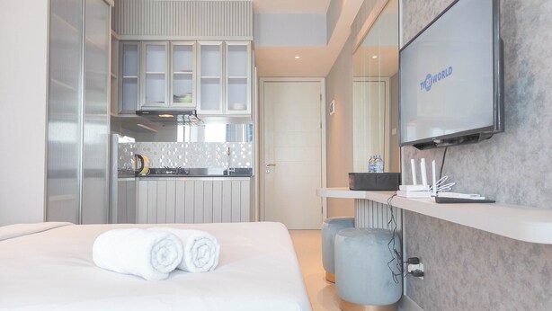 A modern hotel room with a bed, a TV, a kitchen area, and a bathroom. - Beautiful And Modern Studio At Benson Supermall Mansion Apartment (Surabaya)