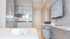A modern hotel room with a bed, a TV, a kitchen area, and a bathroom. - Beautiful And Modern Studio At Benson Supermall Mansion Apartment (Surabaya)
