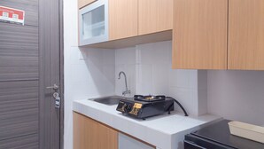 Une cuisine de taille réduite, équipée d’un évier, d’une cuisinière à gaz et de meubles de rangement en bois.