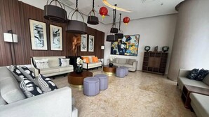Una sala de estar moderna con un conjunto de sofás, otomanas, una mesa de centro y obras de arte en las paredes.