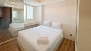 Una habitación de hotel moderna con una cama grande, un armario empotrado, una ventana y un espejo.