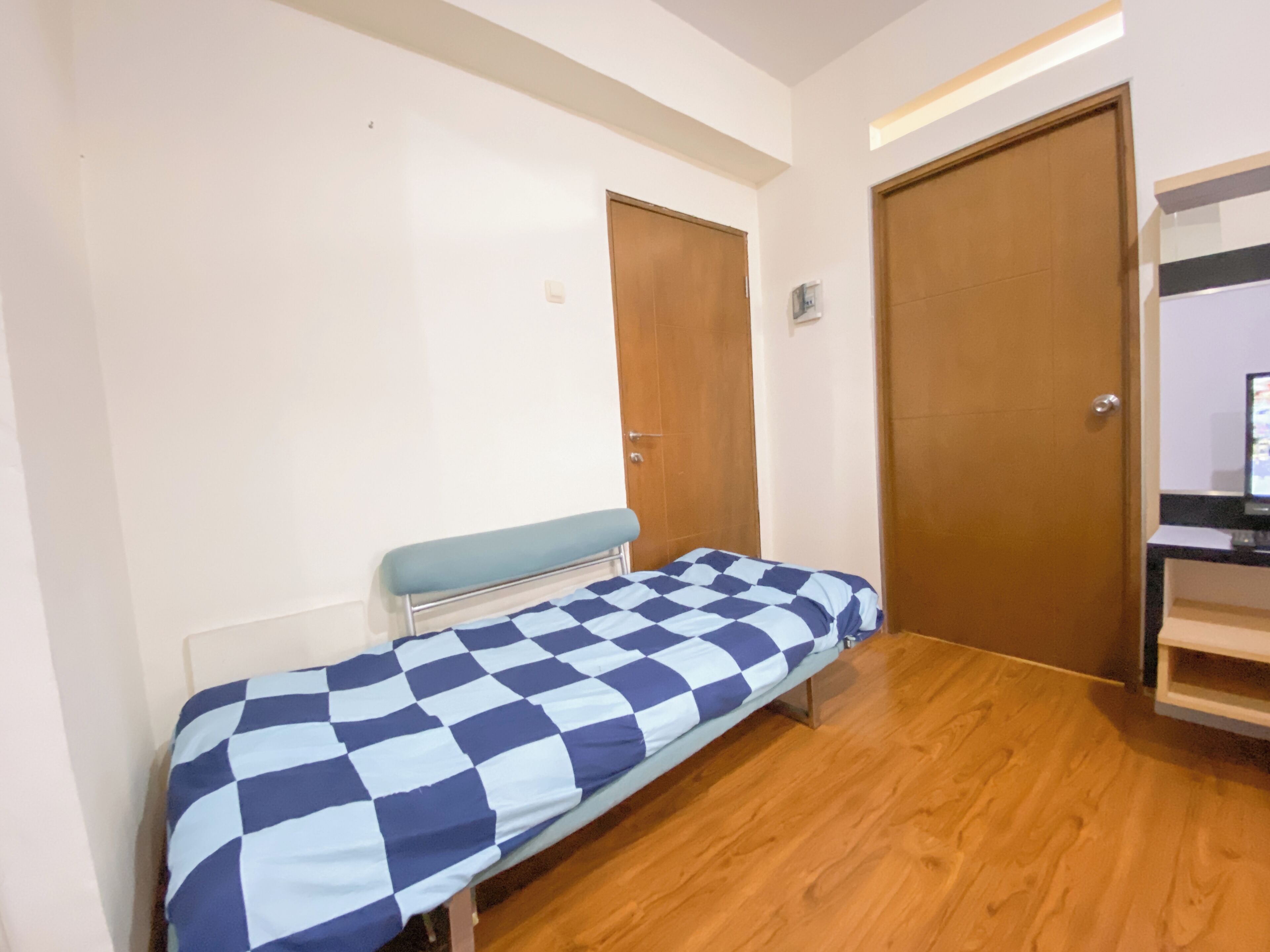 Une pièce avec un lit, un plancher en bois et deux portes.