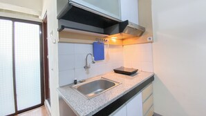 Una cocina con un lavamanos de acero inoxidable, una tabla de cortar azul y una campana extractora sobre la estufa.