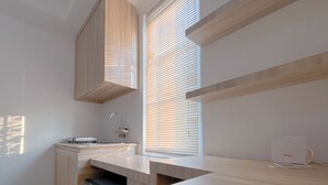 A modern kitchen with a built-in sink, wooden cabinetry, and a window with blinds. - Simply Look And Homey Studio Paltrow City Apartment (Semarang)