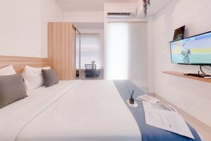 A hotel room with a bed, a TV, a desk, and a window. - Simply Studio Apartment At Serpong Garden (Cisauk)