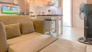 Una sala de estar moderna con un sofá, un comedor con una mesa y sillas, una cocina con estufa y armarios, y un televisor en la pared.