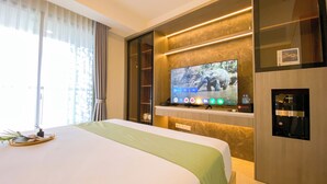 Quarto de hotel com uma cama grande, televisão de tela plana fixada em uma parede de mármore e um minibar.
