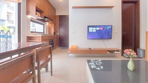 Een moderne woonkamer met een televisie, houten meubels en een vaas met bloemen.