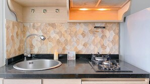 A compact kitchen with a sink, a gas stove, and a decorative backsplash. - Best Choice And Modern 2Br Green Pramuka City Apartment (Jakarta)