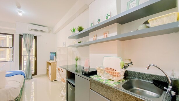 A modern kitchen with a granite countertop, stainless steel sink, and built-in shelves above the counter. - Relaxing Studio At Transpark Cibubur Apartment (Depok)