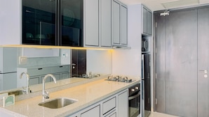 A modern kitchen with grey cabinets, stainless steel appliances, and a granite countertop. - Good Deal And Elegant Studio Ciputra World 2 Apartment (Jakarta)