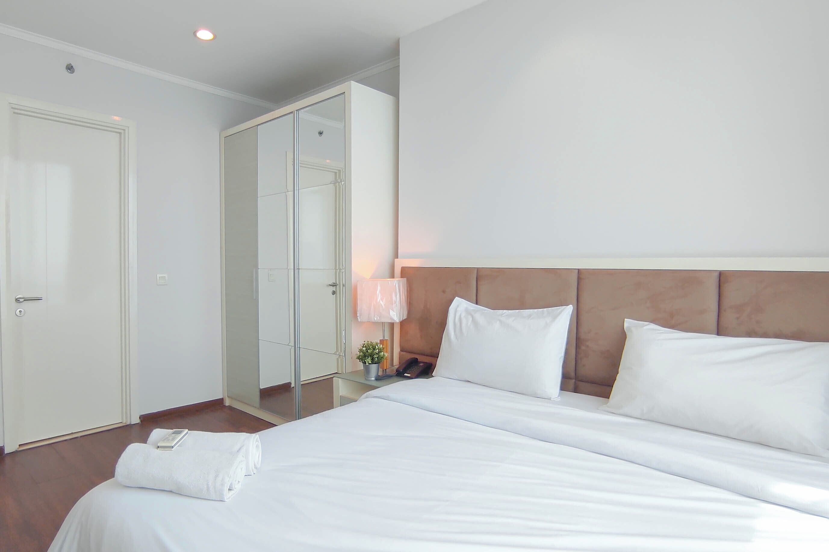 A hotel room with a large bed, a bedside table with a lamp, a phone, and a mirror.