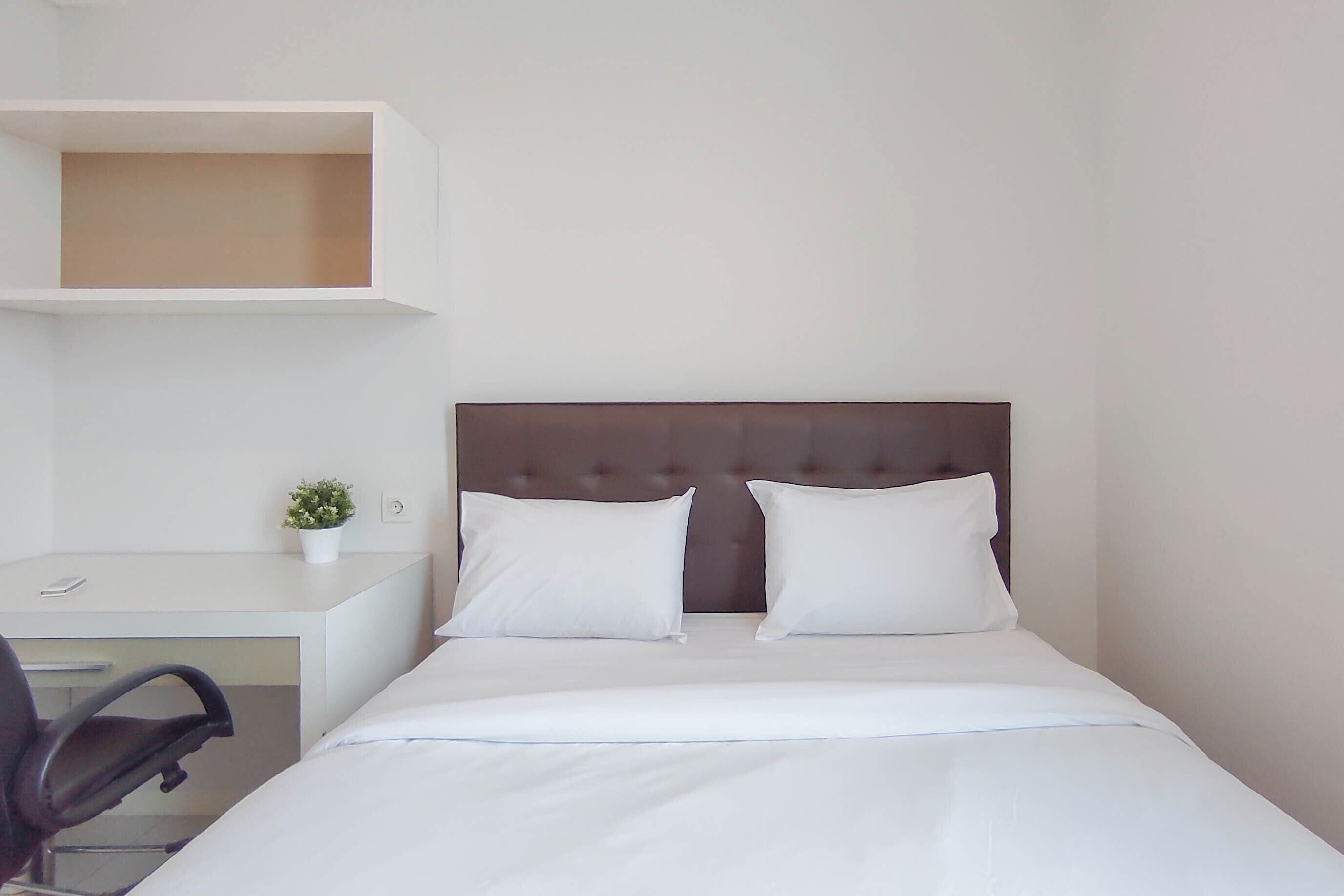 A neatly arranged hotel room with a bed, a desk, and a chair.