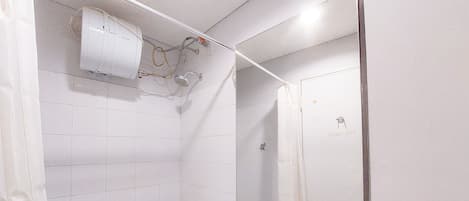 A bathroom with white tiles, a sink, a mirror, and a shower.