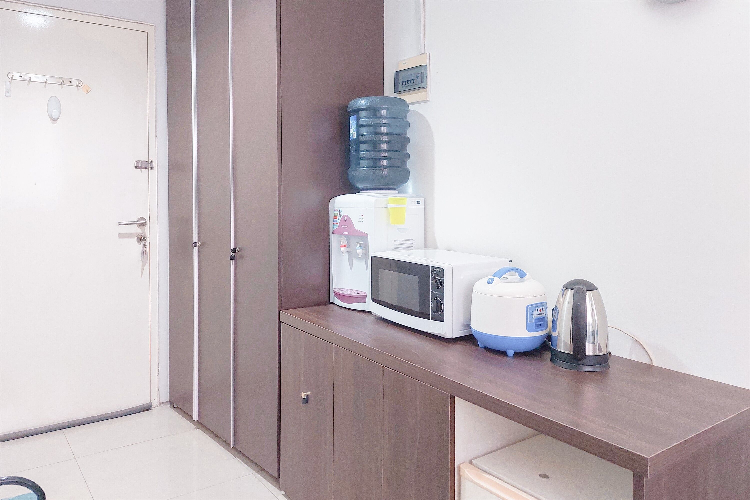 A kitchenette with a microwave, kettle, and water dispenser on a wooden counter.
