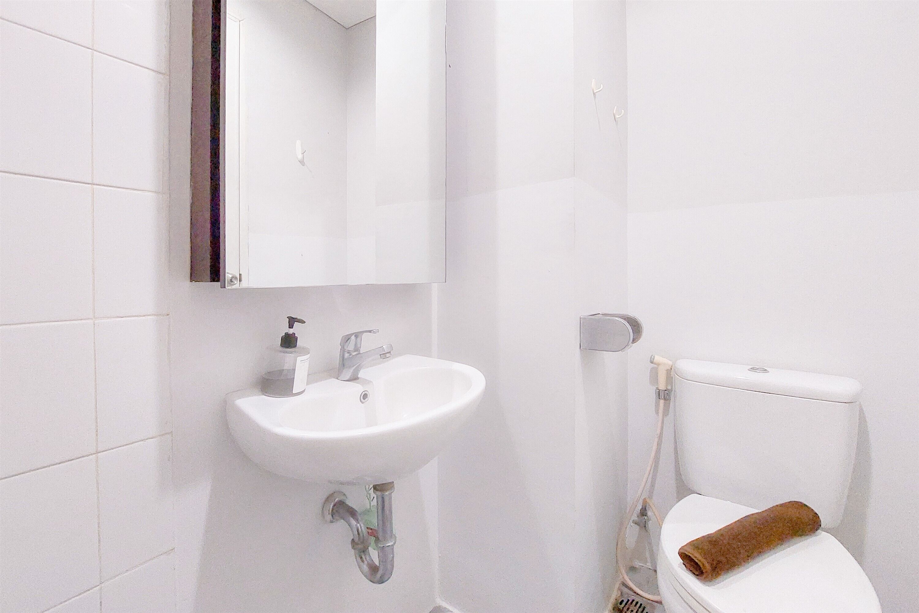 A bathroom with a white sink, a mirror, and a toilet with a towel on it.