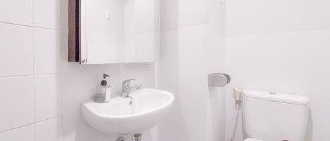 A bathroom with a white sink, a mirror, and a toilet with a towel on it.