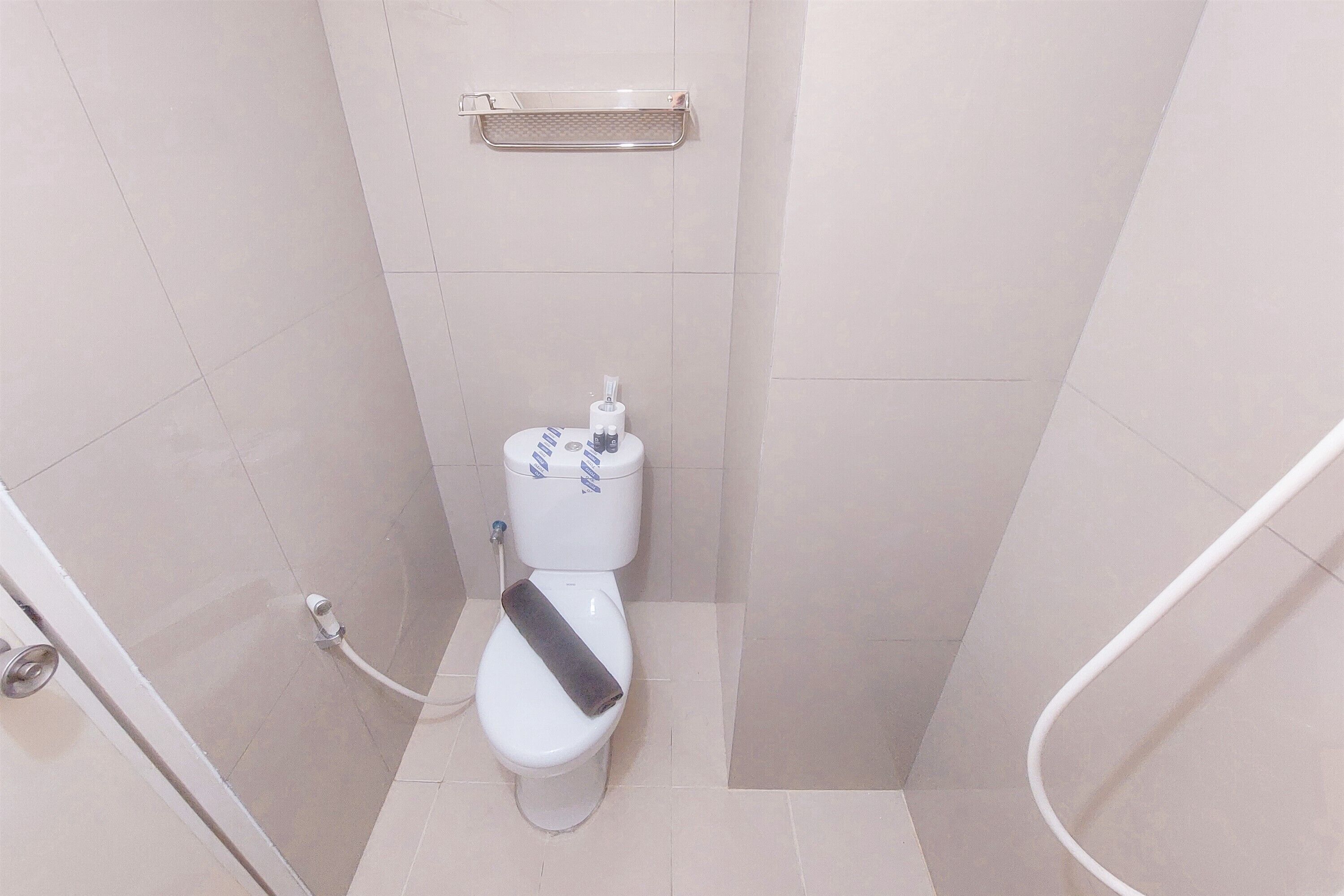 Une petite salle de bain moderne, équipée de toilettes, d’une douche et d’un porte-rouleau de papier toilette fixé au mur.