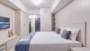 A modern hotel room with a large bed, a flat-screen TV, and built-in wardrobes. - Restful And Tidy Studio At Apartment Baileys (South Tangerang)