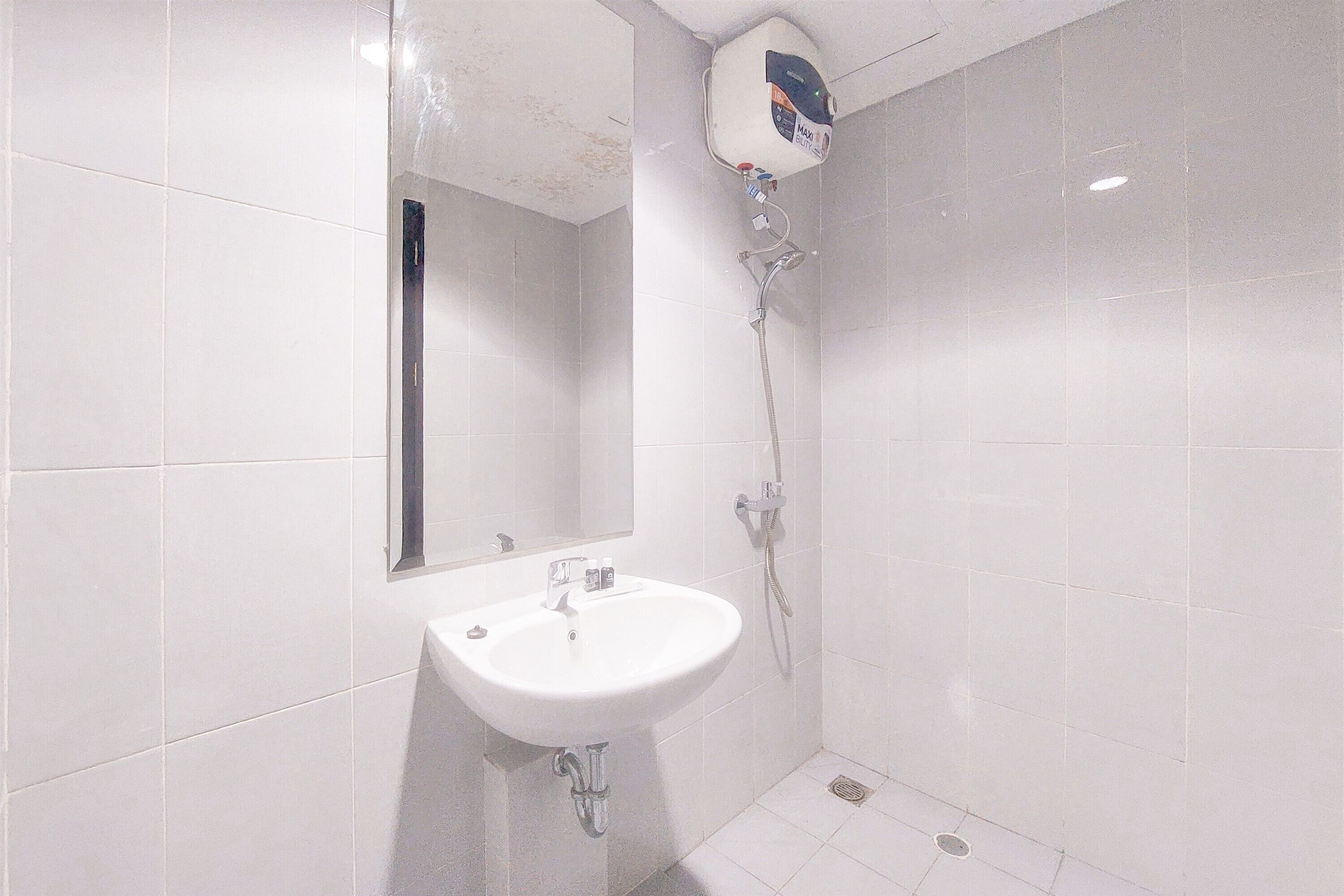 Un baño con lavamanos blanco, espejo y ducha.
