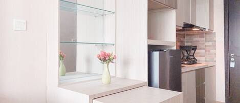 Una cocina moderna con estufa integrada, refrigerador y estantería de vidrio.