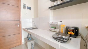 A kitchen with a sink, a rice cooker, and a toaster. - Highrise Studio At Apartment Beverly Dago (Bandung)