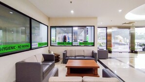 A modern hotel lobby with a seating area, large windows, and visible storefronts. - Highrise Studio At Apartment Beverly Dago (Bandung)