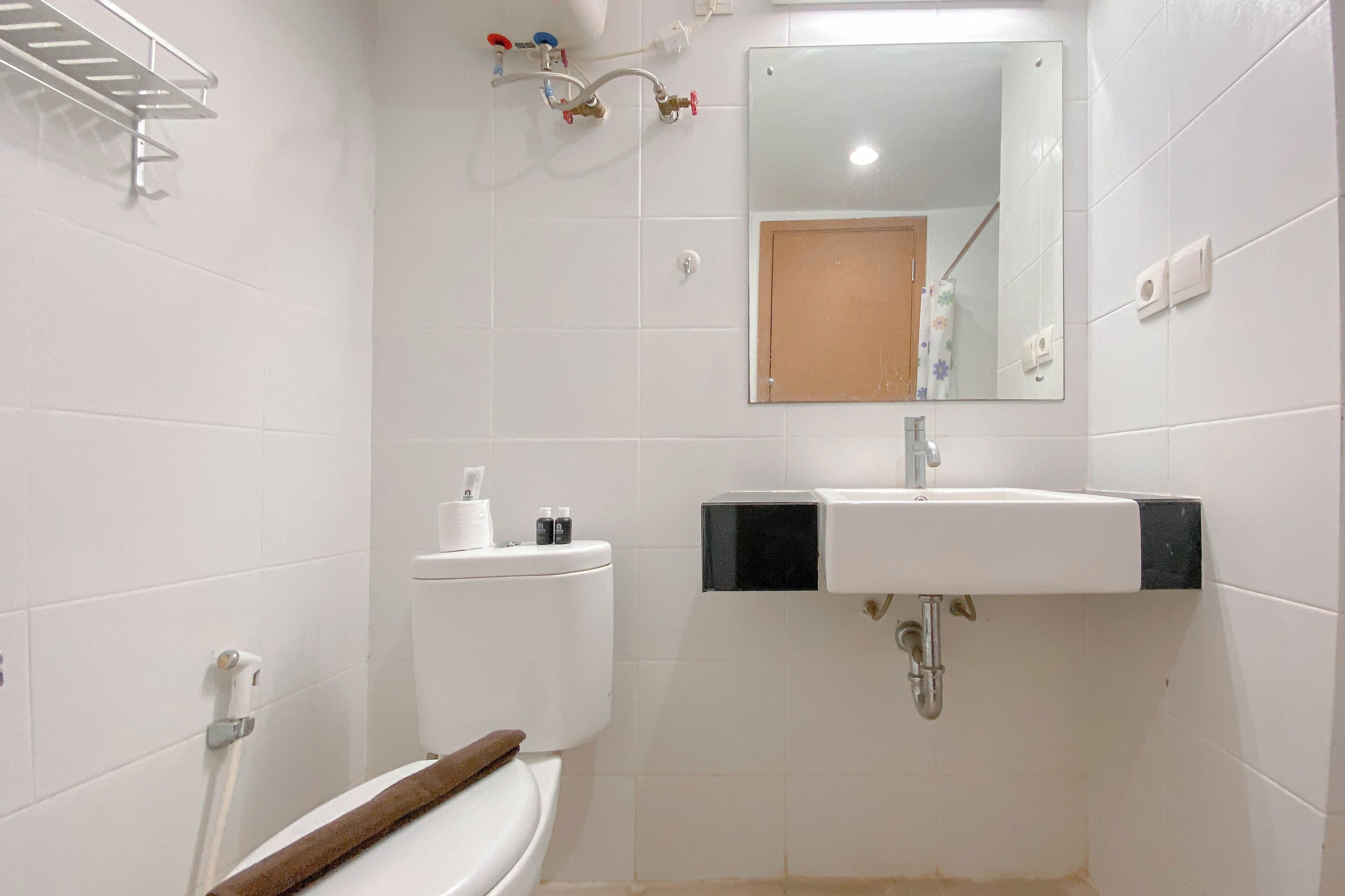 A bathroom with a white toilet, a sink, a mirror, and a towel rack.