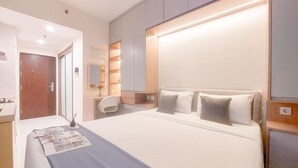 A modern hotel room with a large bed, bedside tables, a desk, and a chair. - Good Place And Strategic Studio At Sky House Bsd Apartment (Pagedangan)