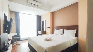 Habitación de hotel con una cama grande, televisión de pantalla plana, escritorio y ventana con cortinas.