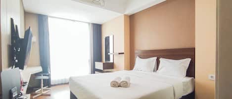 Habitación de hotel con una cama grande, televisión de pantalla plana, escritorio y ventana con cortinas.