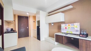 Un moderno vestíbulo de hotel con televisor de pantalla plana, kitchenette y mostrador de recepción.