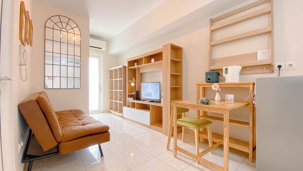 Una sala de estar moderna con un sofá de cuero marrón, una mesa de comedor de madera con dos sillas, un televisor y estanterías empotradas.