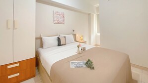 Habitación de hotel con cama, mesita de noche, aire acondicionado de pared y un cuadro en la pared.