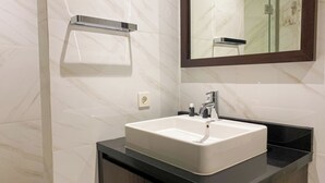 A bathroom with a white sink, a mirror, and a towel rack.