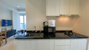 A modern kitchen with a black countertop, stainless steel sink, and a built-in microwave.