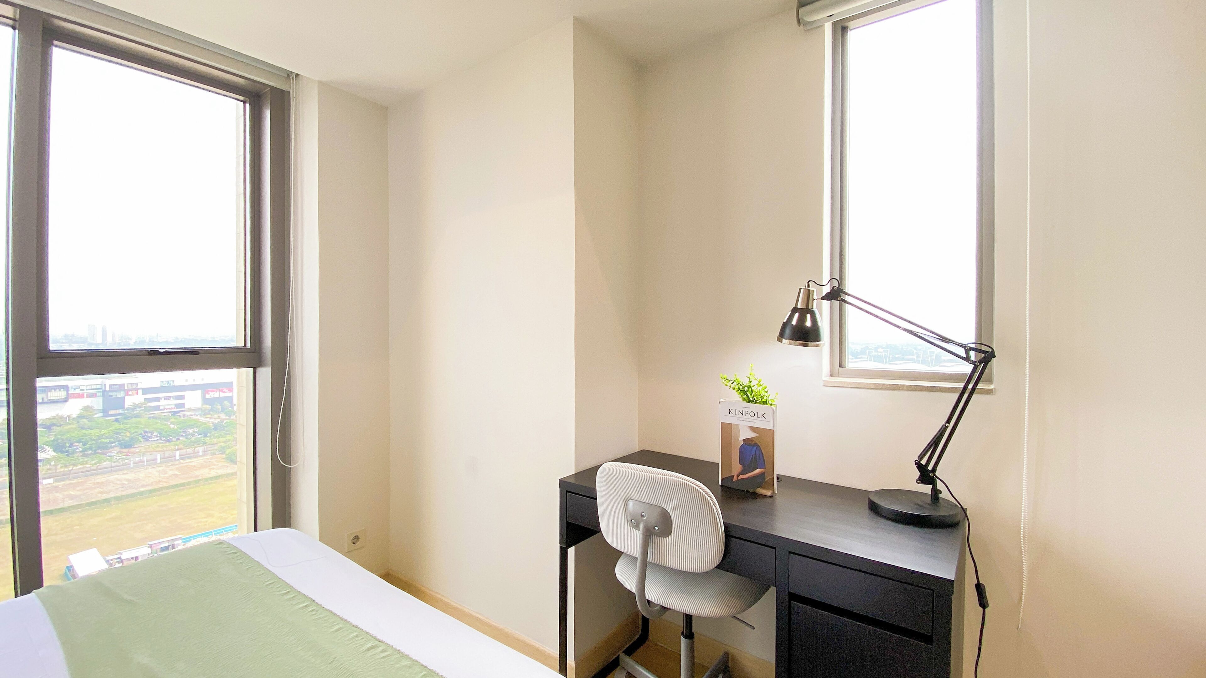 Una habitación de hotel con cama, escritorio, silla, ventana y lámpara de escritorio.