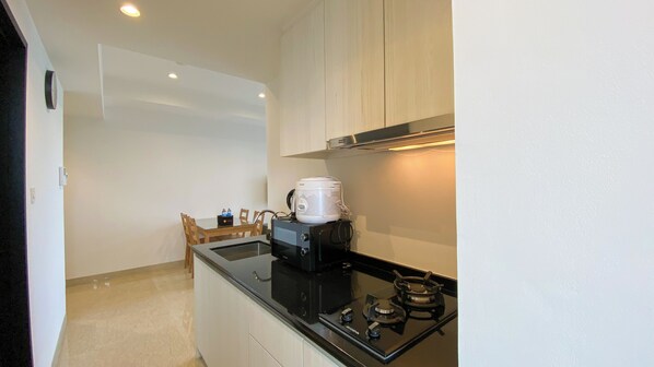 A compact kitchen with a black countertop, a gas stove, and a coffee maker.