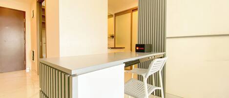 Una habitación de hotel moderna con un escritorio pequeño, una silla, un radiador y una puerta.
